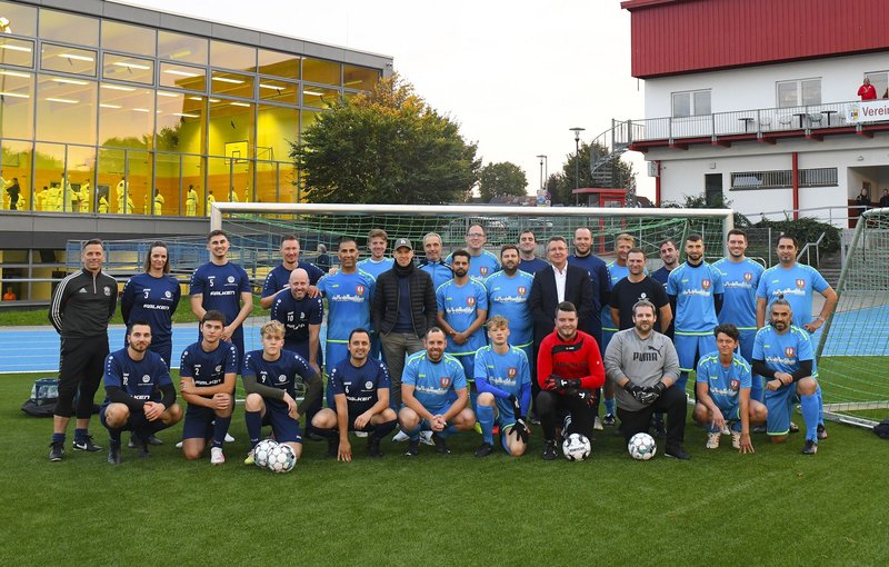 Die Mannschaften tragen mittelblaue und dunkelblaue Trikots und haben sich zum Gruppenfoto aufgestellt.