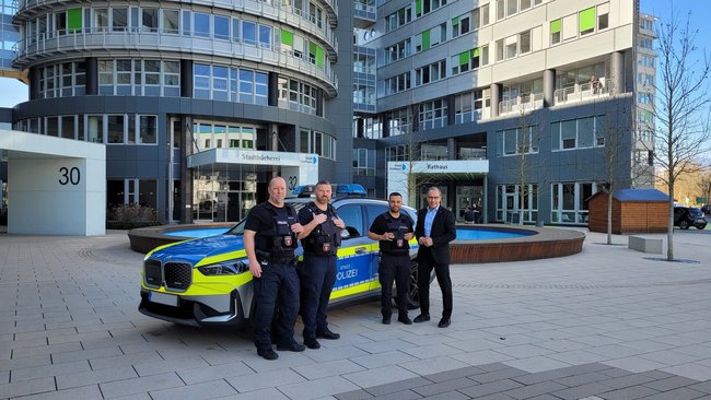 Thorsten Löwenbrück und die Stadtpolizisten El Harchi und Post mit Bürgermeister Adnan Shaikh vor dem neuen Fahrzeug, das vor dem Rathaus in der Ludwig-Ehrhard-Straße steht
