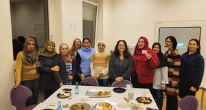 Elf Frauen stehen hinter einem Tisch, auf dem Teller stehen. In der Mitte steht Nil Esra Dağistan.