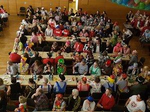 Menschen in bunten Kostümen sitzen an Tischen