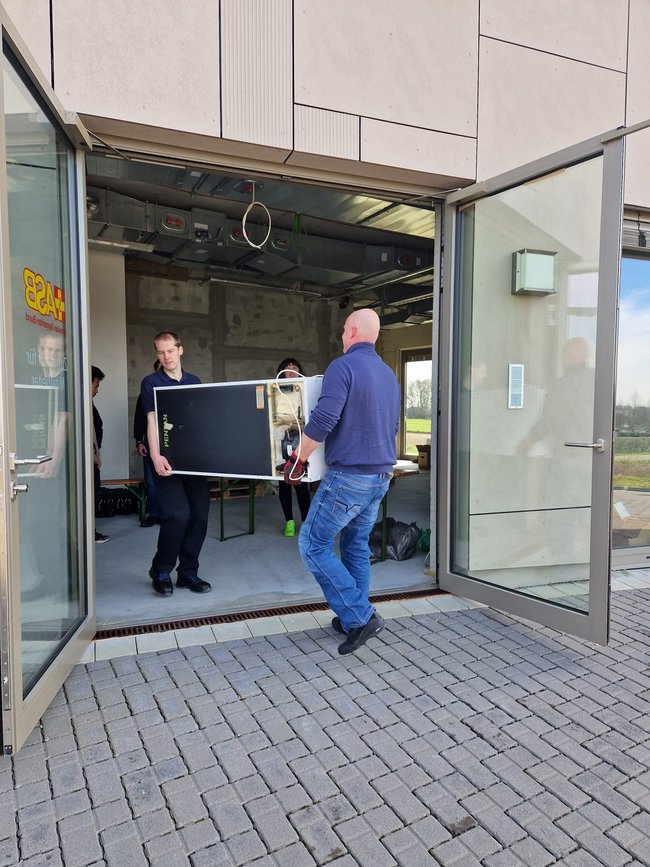 Zwei Männer tragen einen Kühlschrank.