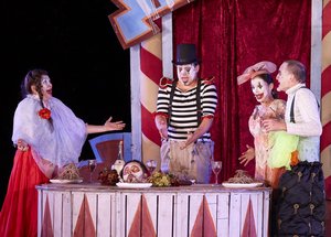 Vier Clowns stehen um einen gedeckten Tisch