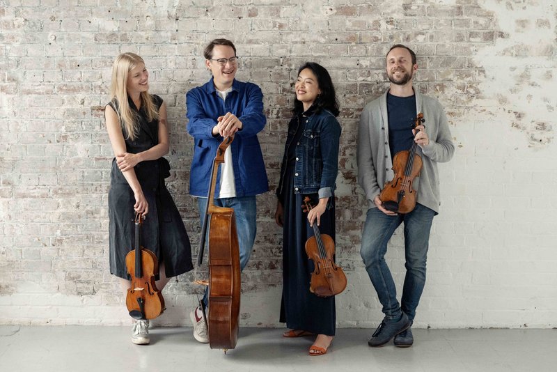 Das Doric String Quartet mit Instrumenten vor einer Betonwand