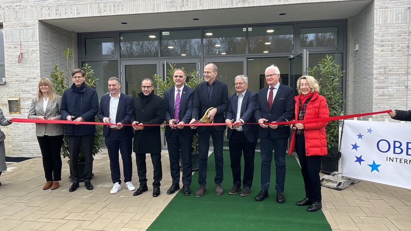 Lara Bielak, Dr. Matthias Hildner, Axel Fink, Adnan Shaikh, Alexander Immisch, Dr. Gerhard Obermayr, Armin Bielak, Mathias Geiger und Christiane Augsburger stehen in einer Reihe und schneiden gemeinsam das Band zur Eröffnung durch.