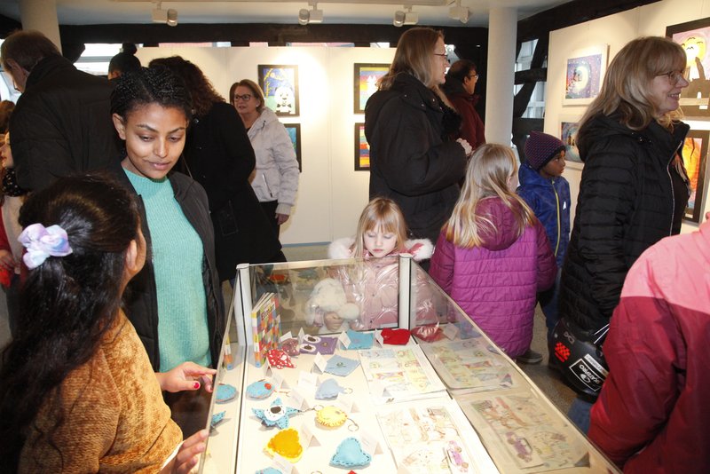 Kinder und Erwachsene schauen in eine Vitrine.