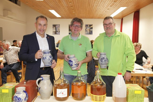 Bürgermeister Shaikh, Thilo Heinzel und Udo Gauf mit Bembeln in der Hand vor einem Tisch mit Apfelweinen.
