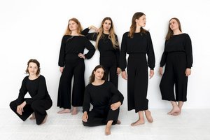 Sechs Frauen in weiter, schwarzer Kleidung stehen in unterschiedlichen Posen vor einem weißen Hintergrund.