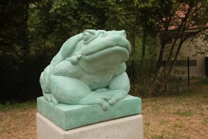 Eine Skulptur eines Frosches, der auf einem Sockel sitzt.