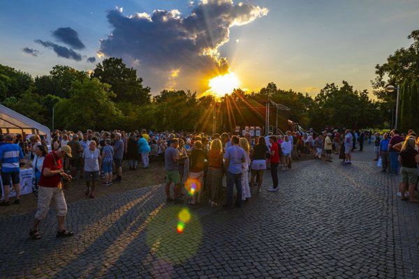 Viele Menschen stehen bei Sonnenuntergang im Skulpturenpark