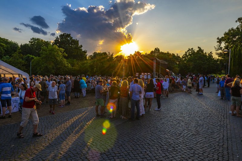 Viele Menschen stehen bei Sonnenuntergang im Skulpturenpark