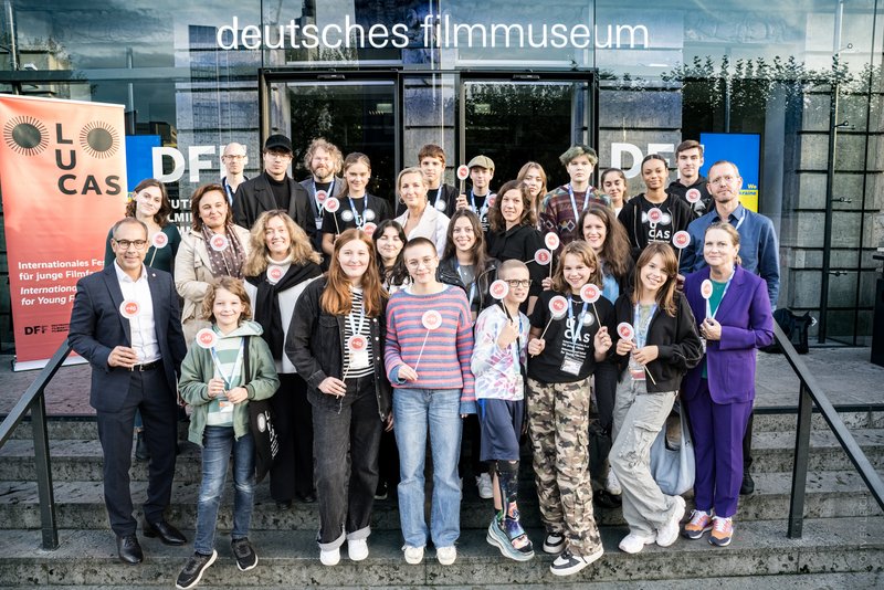 Jurymitglieder, das Veranstaltungsteam des Filmfestivals und Gäste posieren zum Gruppenfoto auf den Stufen vor dem DFF.