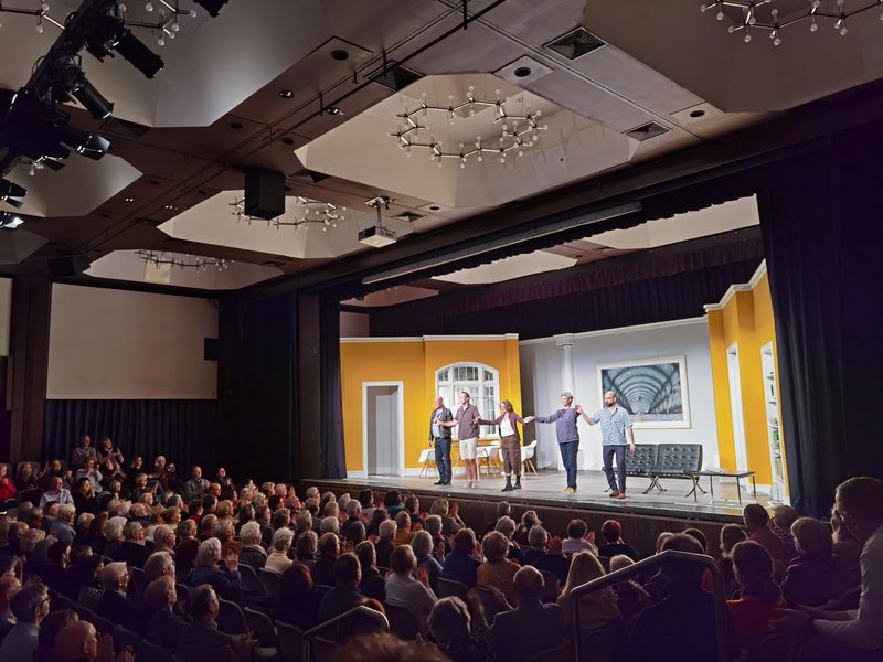 Fünf Schauspielerinnen und Schauspieler halten sich auf der Bühne an den Händen und verbeugen sich. Der Saal ist voll besetzt.