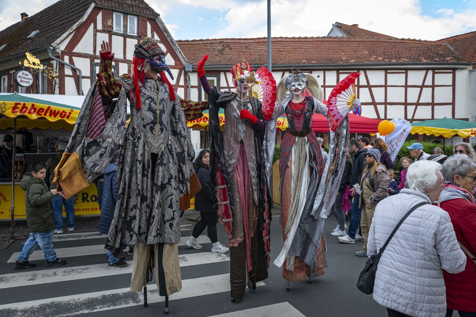 Stelzenfiguren in grauen und roten venezianischen Kostümen.