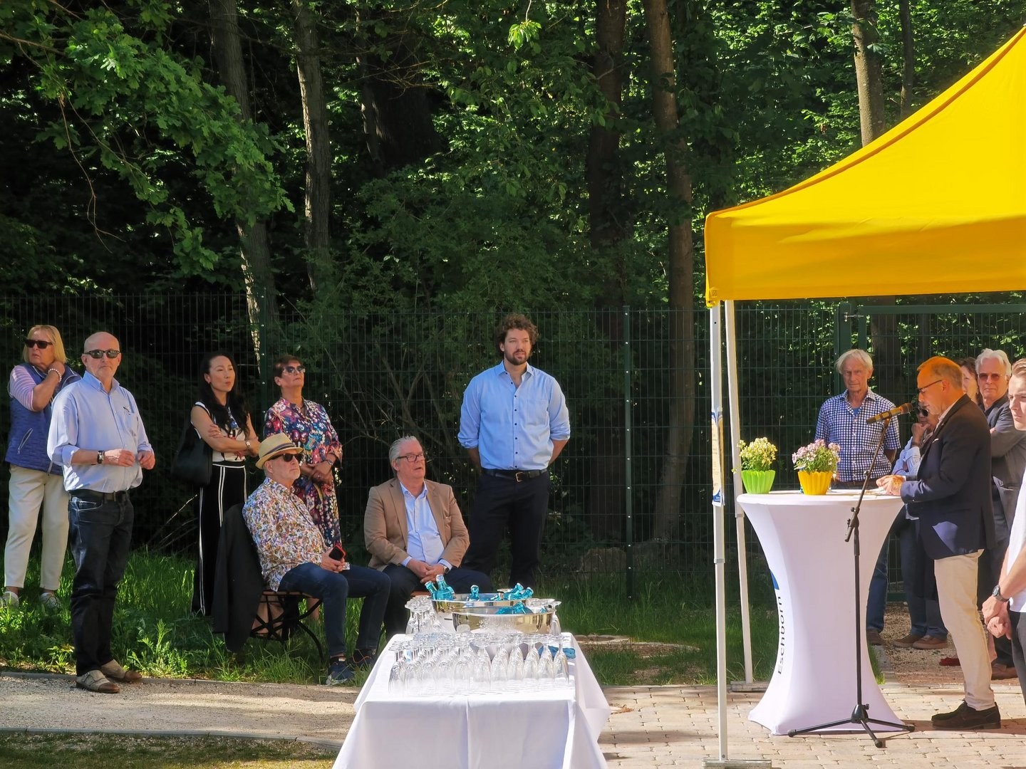 Bürgermeister Shaikh eröffnet die Sommerausstellung. Die Menschen hören ihm zu.